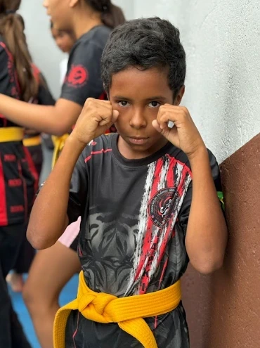 Criança de punhos cerrados em com vestimentas de artes marciais.