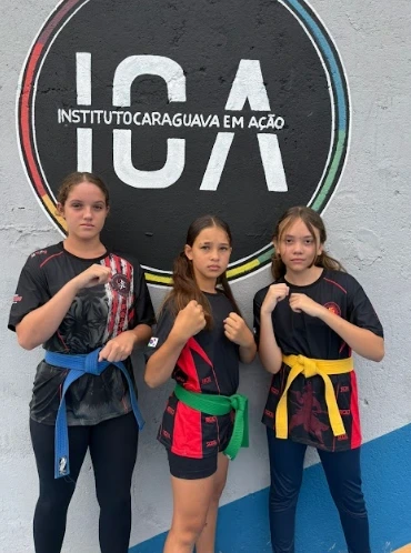 Meninas do ICA posando em trajes de roupas de artes marciais.